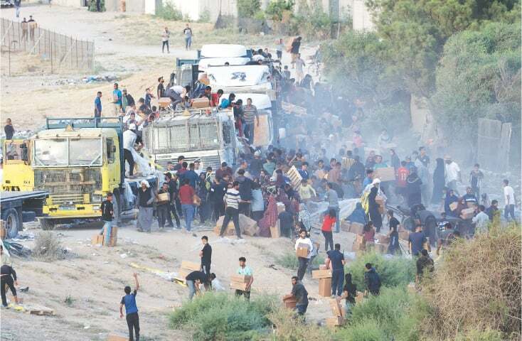 This May 18 file photo shows Palestinians climbing onto trucks to grab aid delivered into Gaza through a US-built pier.—Reuters